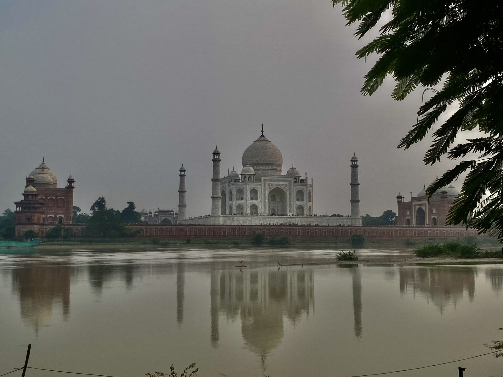Taj Mahal at the break of dawn — marble glowing pink and amber in the early morning light, with an empty garden in the foreground